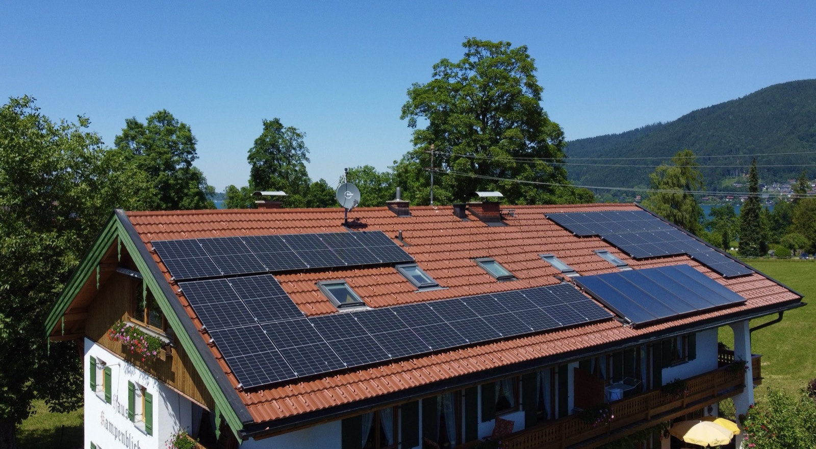 Mehrfamilienhaus mit PV, See und Berge im Hintergrund
